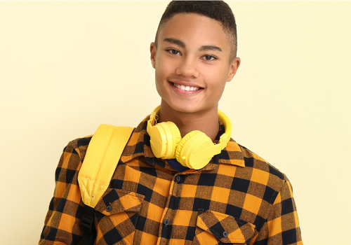 Young man with yellow headphones smiling at camera