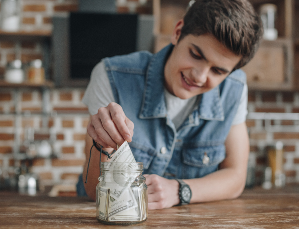 teen boy putting money in jar