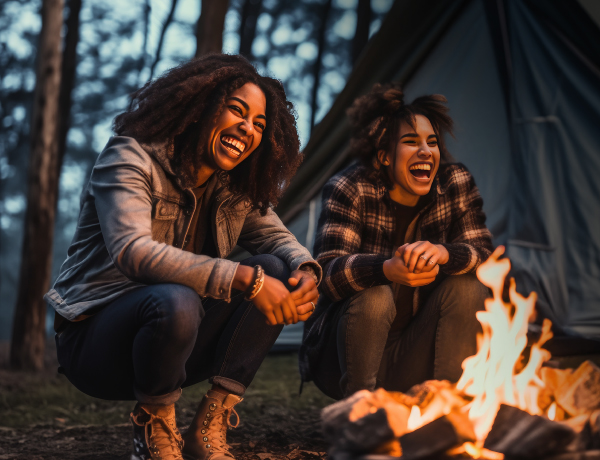 two women laughing around a campfire