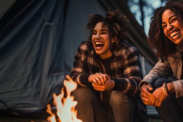 two women laughing around a campfire