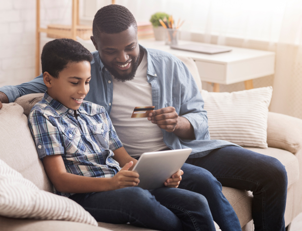 father teaching son to use credit card on tablet
