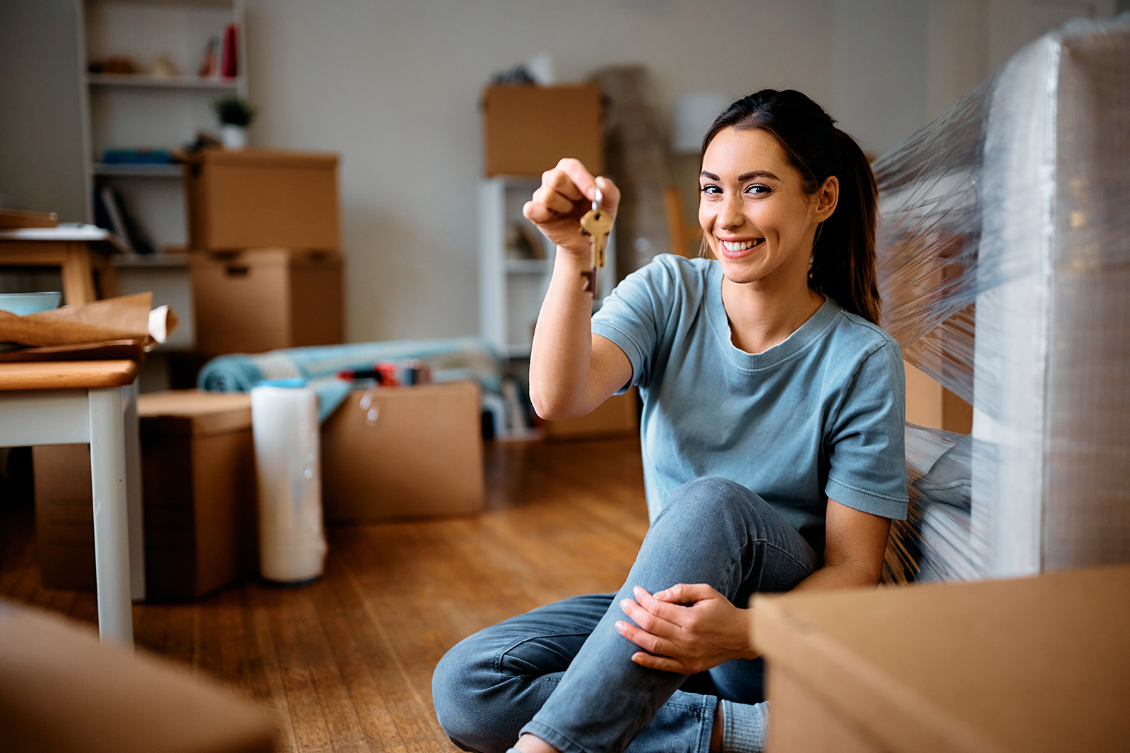 Young happy woman holds key while moving into new home.
